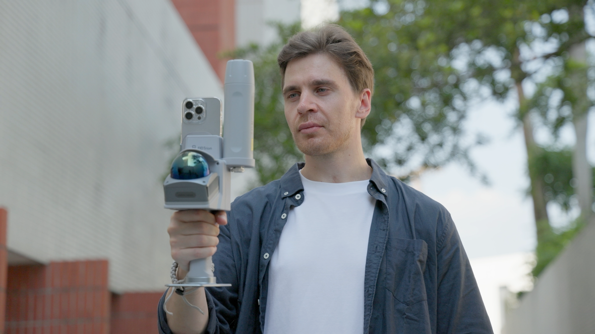 Man using a handheld 3D LiDAR scanner with a mounted smartphone for outdoor real-time point cloud capture