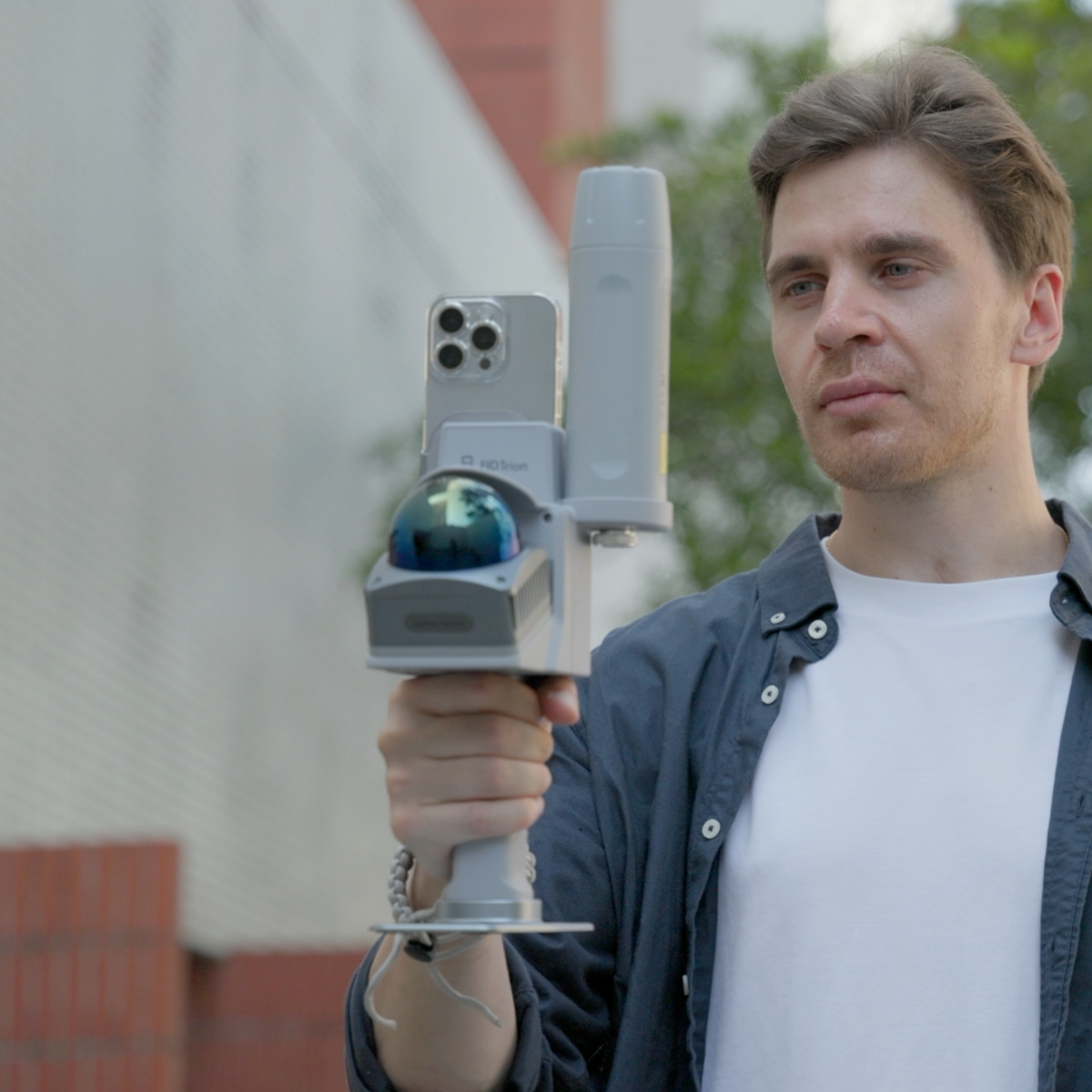 Man using a handheld 3D LiDAR scanner with a mounted smartphone for outdoor real-time point cloud capture